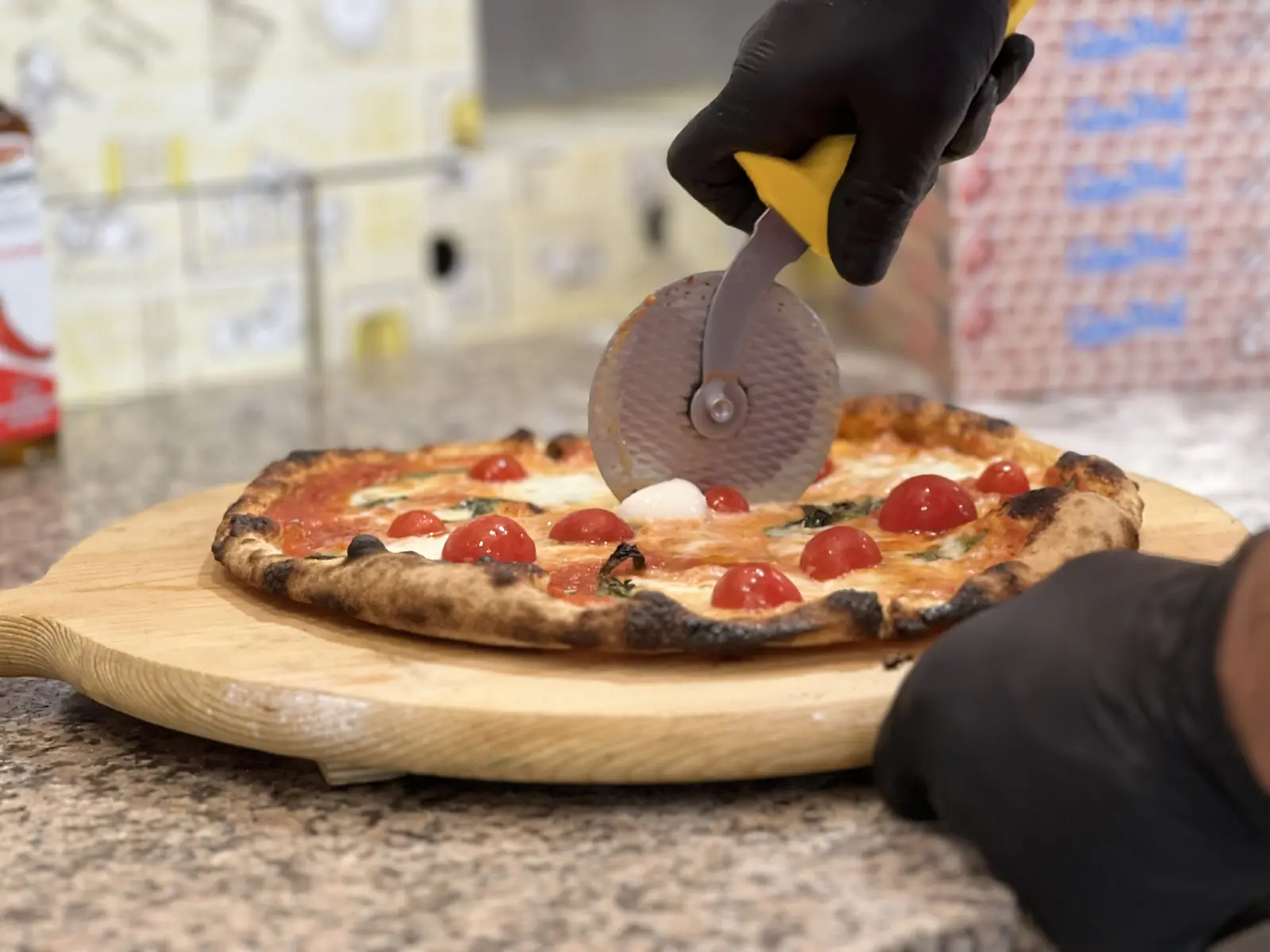 Pizza con pomodorini tagliata con la rotella sulla pala di legno