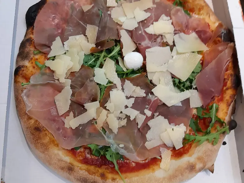 Pizza con crudo, rucola e scaglie di grana